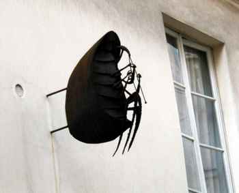 Large metal bug sculpture on shop wall in Latin Quarter.
